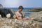 Man at the sea balances stones on a rock