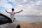 Man seated on the engine hood of a rented car on a road trip in israel