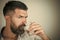 Man with serious emotion. Man with long beard hold water glass on grey background.