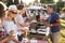 Man Serving On Barbeque Stall At Summer Garden Fete