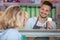 man serving female customer in ice-cream parlour