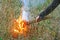 Man sets fire to dry grass.