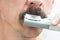 A man is shaping his mustache with a trimmer. Close-up.