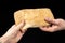 Man is sharing fresh bread ciabatta on black background. Two hands.