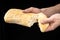 Man is sharing fresh bread ciabatta on black background. Two hands.