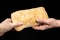 Man is sharing fresh bread ciabatta on black background. Two hands.