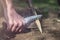 Man sharpening a stake outdoors, close up.