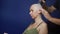 Man shaves a bald woman with an electric razor on a blue background. chemotherapy effects concept.