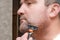 Man shaves beard with razor. Strip of clean leather and bristles on cheek. Close-up