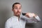 Man shaving face with electric razor on gray