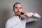 Man shaving face with electric razor on gray