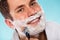 Man shaving using razor with cream foam.