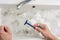 The man is shaving, view of the hands with a razor and the wash basin with dirty water