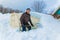 A man sheds snow from a greenhouse with a shovel o