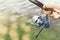 A man in a shirt is holding a fishing rod with a blue reel on a background of water. Concept fishing equipment, outdoor