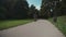 Man in shirt and with rucksack rides bicycle on cycle path in city garden in Munich, Germany. Student cyclist cycling in