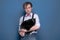 Man in shirt, suspender and pink bow tie holding and looking to cute black cat on blue background with copy space