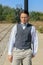 Man in shirt and vest with bow tie and glasses, standing leaning