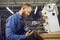 Man shoemaker in uniform holding shoe working at footwear factory workplace