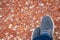 Man shoes on floor. Selective focus on grey sneakers or mens summer shoes and blue jeans on blurred colorful red brown marble