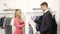 Man shop assistant showing shirt to woman at the mall. man in a business suit looking shirt