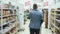 Man shopping at supermarket and talking on phone, backside view, steadicam shot