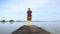 Man in short cargo pants walking on wooden pier and observes the surface of lake