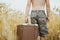 Man in shorts holding retro suitcase in field of