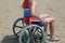 Man with shorts on wheel chair on sandy beach in summer