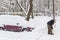 Man with a shovel cleans snow from road near car on parking