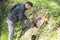 Man with a shovel in his hands digs a hole in the ground in search of military items. The metal detector lies next to it.