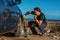 Man with shovel sits next to his car stuck in the sand