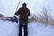 A man with a shovel stands on a narrow path dug in the snow.