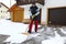 A man shovels snow in front of the garages