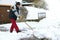 A man shovels snow in front of the garages