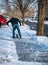 Man shovels snow from sidewalk by house