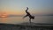 Man showing acrobatics at seaside during sunset