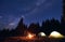 Man is showing his friends Milky Way over tent city. Outdoor recreation