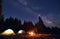 Man is showing his friends Milky Way over tent city. Outdoor recreation