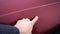 Man shows scratches with rust in a car paint. Finger show scratch on red car