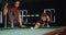 A man shows woman how to hold a cue and break a triangle in billiards