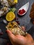 A man shucking fresh oysters with his bare hands on stone table, lemon slices, micro greens, ice, cranberries on table