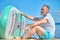 Man sideways to camera sitting with paddle board