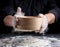 Man sifts white wheat flour through a wooden sieve