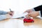 Man signing a car insurance policy, the agent is holding the document. concept document sales loan and rental. focust red car on