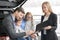 Man signing document of automobile purchase, happy family.