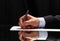 Man signing a document or writing correspondence with a close up view of his hand