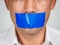 Man is silenced with adhesive red tape across his mouth sealed to prevent him from speaking. Freedom Concept