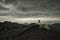 Man silhouette jumping under dramatic sky on volcanic landscape by wild camp in Etna Park