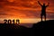 Man silhouette on the mountain top watching the sunrise and 2018 years while celebrating